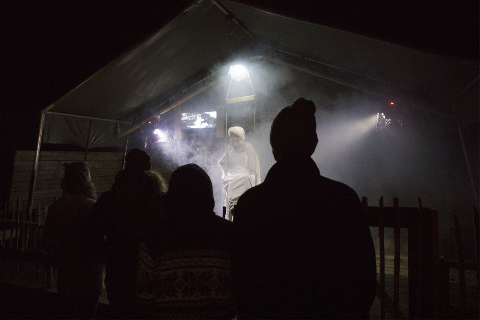 Mensen staan in het donker naar een podium te kijken waarin een mysterieuze vrouw staat in de mist.