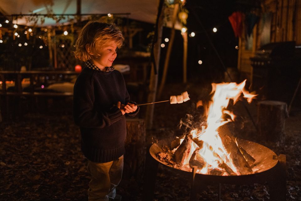 Een jongetje roostert een marshmallow boven een vuurschaal.