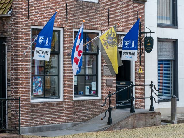 De voorkant van de VVV in Bolsward. Buiten hangen verschillende vlaggen.