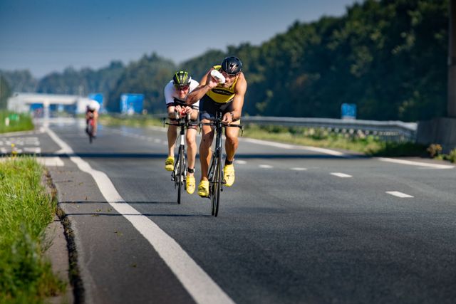Wielrenners op het asfalt van de autoweg en een wielrenner drinkt uit een bidon tijdens Triathlon NOP in Flevoland