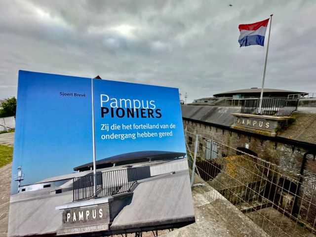 Een foto van het boek 'Pampus Pioniers' met op de achtergrond het forteiland.