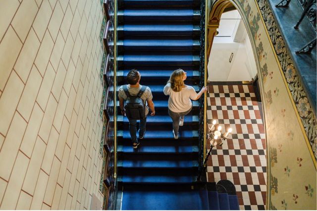 Een man en een vrouw lopen de trap op in de hal van het Drents Museum.