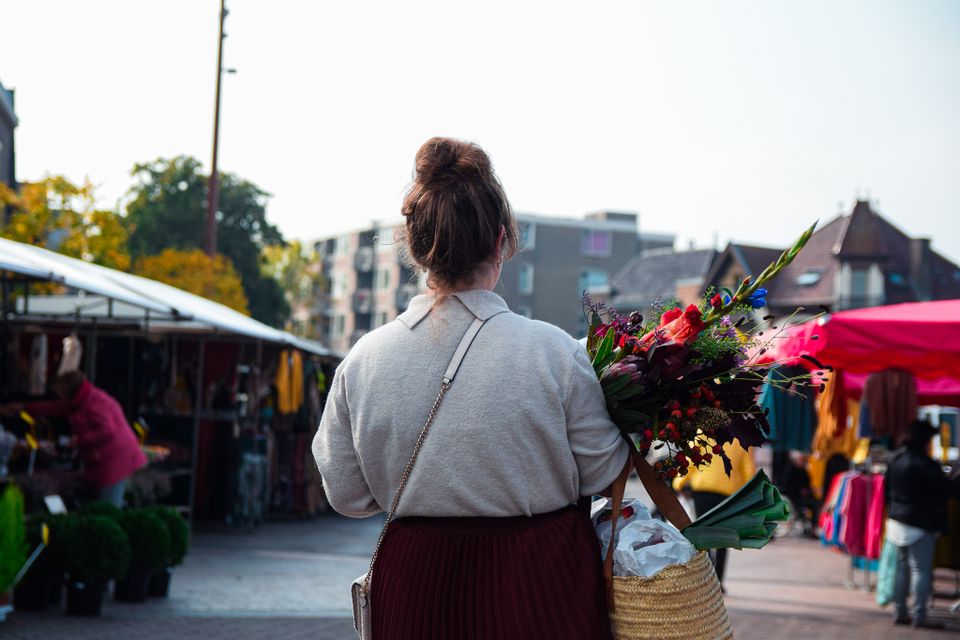 Dame loopt met rieten mand op de markt