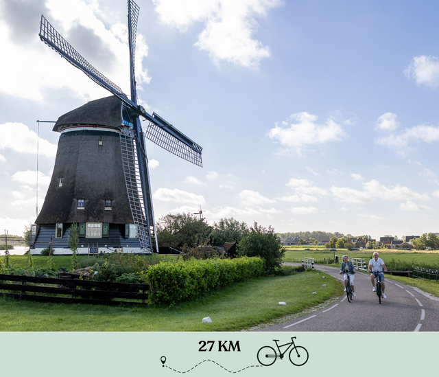 Een man en een vrouw die aan het fietsen zijn bij de Neckermolen in de regio Laag Holland (Noord-Holland).