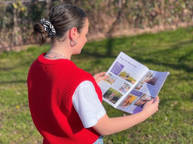 Vrouw in rode trui leest het Land van de Peel magazine