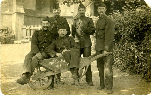 Zwart-witfoto van vijf soldaten in uniform bij een kruiwagen waarop 'mobilisatie 1904' staat.