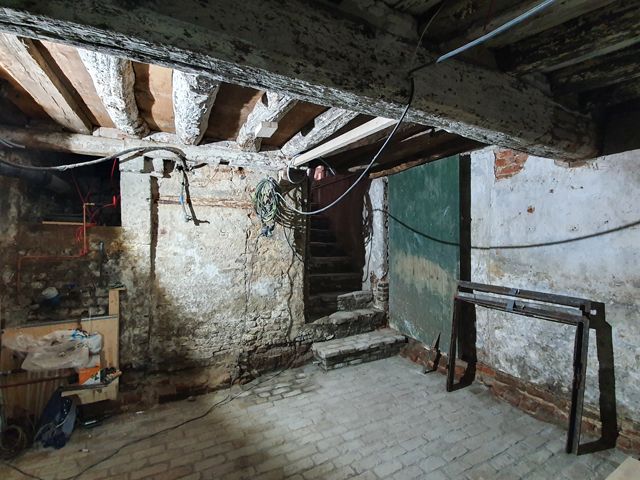 Oude balken uit het ingestorte buurpand zijn gebruikt voor het herstel van het plafond van de kelder