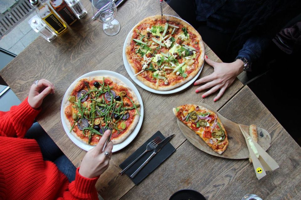 Grote en kleine pizza's met handen bij Woodstone Pizza & Wine in Almere Centrum aan het restaurantplein Belfort