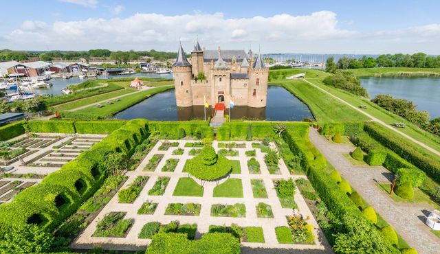 Luchtfoto van Kasteel Muiderslot met op de voorgrond de groene kasteeltuinen