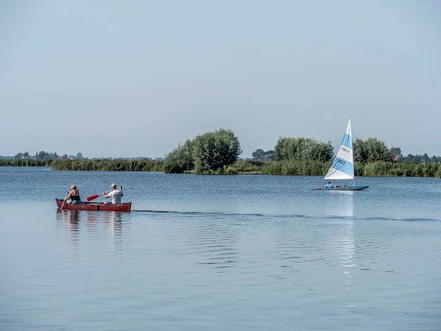 een zeilboot en een kano in het water bij Heeg.