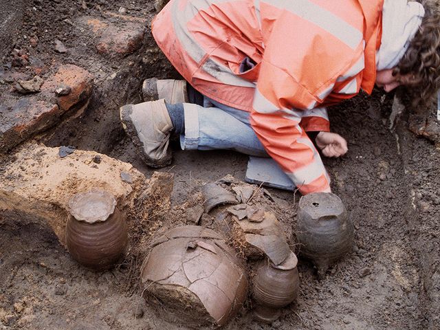 Archeoloog bij gevonden potten tijdens een opgraving