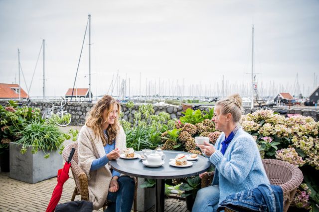 twee vrouwen zitten op een terras in hindeloopen met de haven op de achtergrond