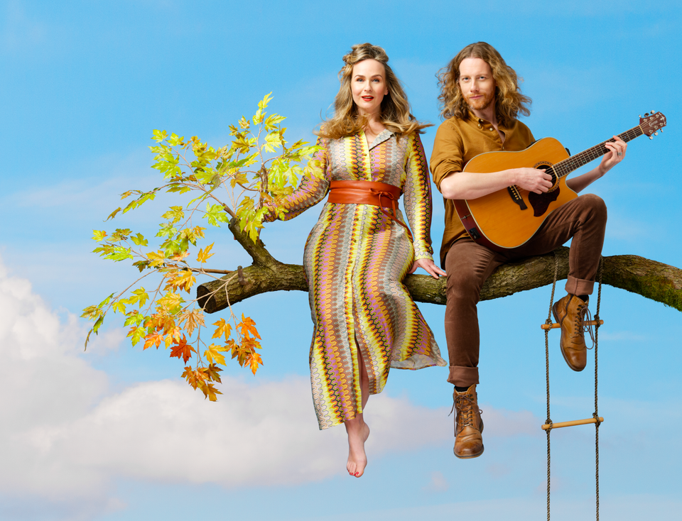 foto van een man met gitaar en een vrouw op een tak
