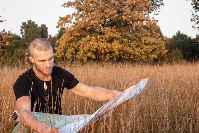 Een man leest een kaart zitten in een natuurgebied in Drenthe.