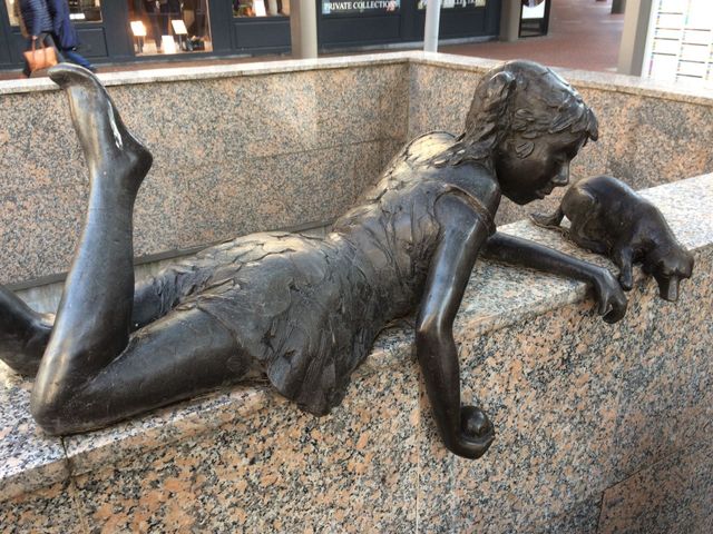 Bronzen sculptuur van een meisje dat met een hond speelt. Meisje spelend met hond van Evert den Hartog (Stadshart Zoetermeer)