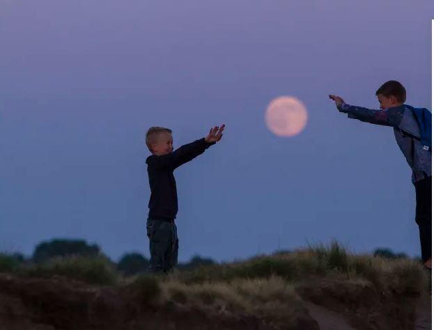 Twee jogentjes houden  de maan vast dmv trucage op de foto