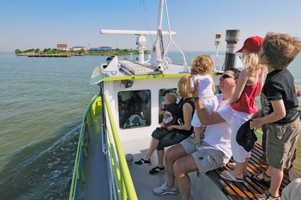Bezoekers kijken vanaf veerboot uit naar Forteiland Pampus aan de horizon