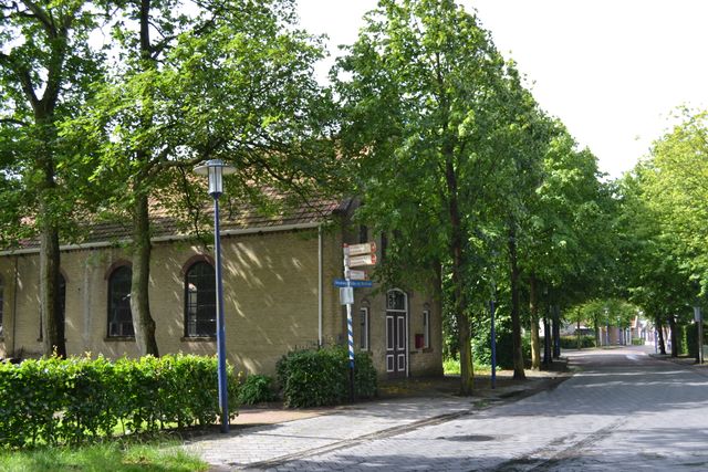 Een straat in Koudum met een oud gebouw.