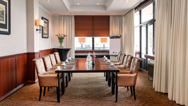 Een ruime kamer waarin een grote tafel staat met daaromheen verschillende stoelen. De ruimte is te gebruiken voor bijeenkomsten. In Hotel van der Valk Emmeloord in de Noordoostpolder.