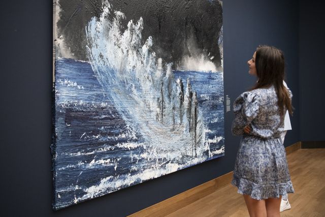 Vrouw kijkt naar groot kunstwerk in tentoonstelling La Grande Bleue