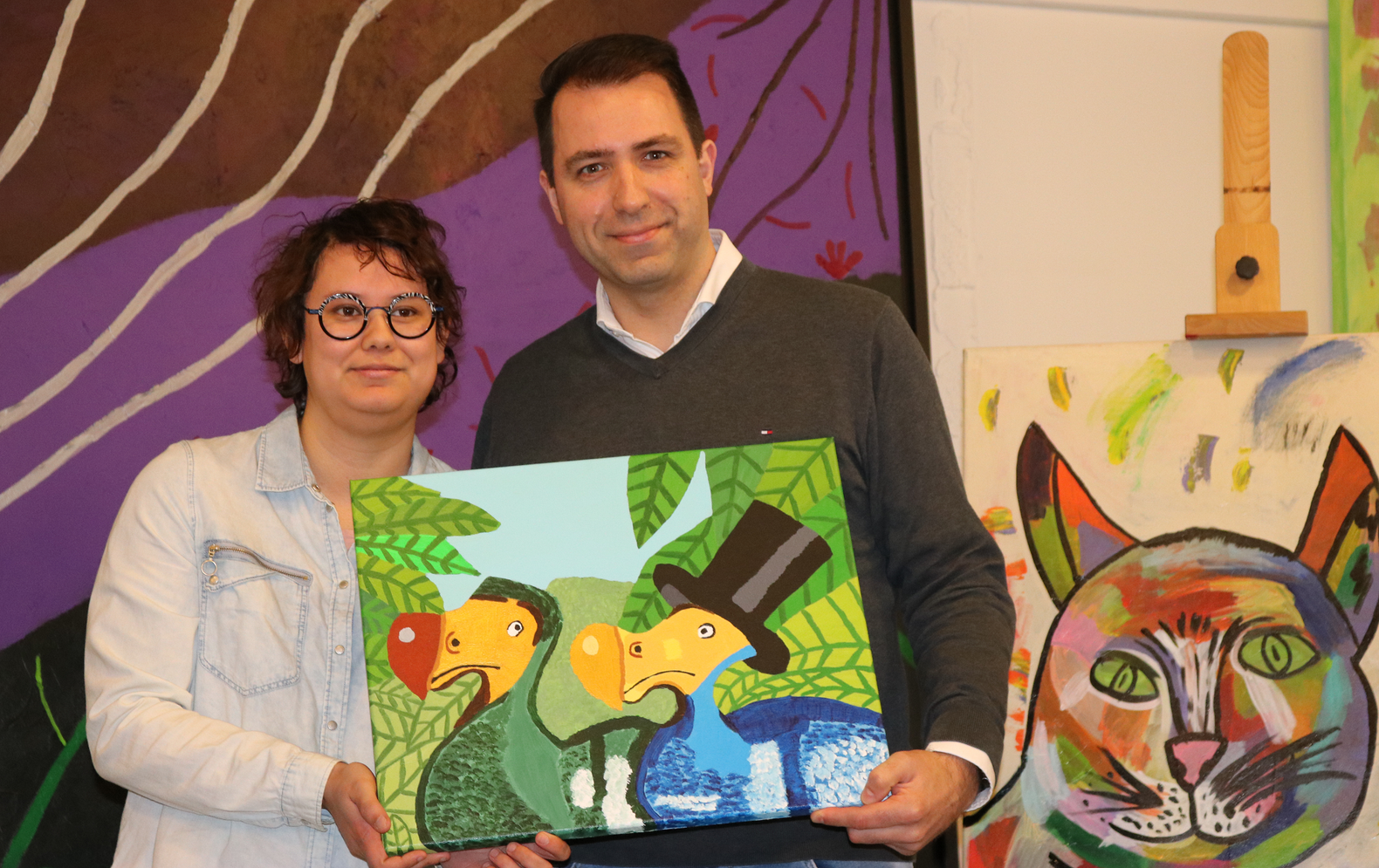 Kunstenaar Amy Feddes en nieuwe eigenaar Jan Jaap die een schilderij samen vasthouden in atelier Verfstreken.