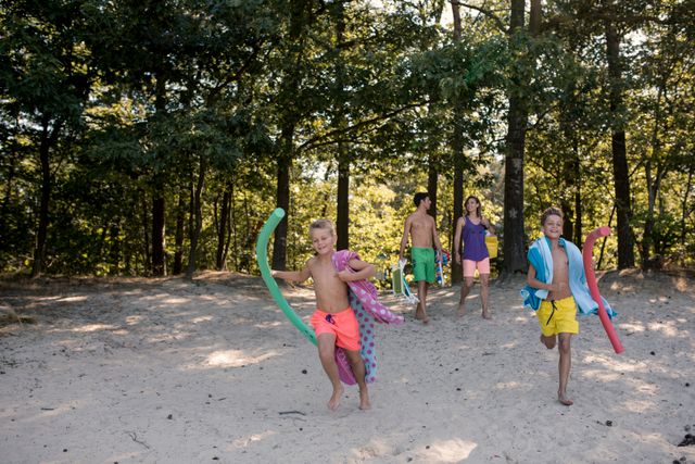 Kinderen rennen op strand richting de zwemplas.