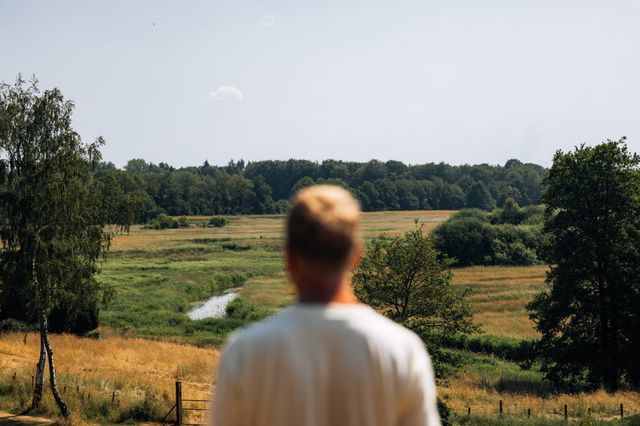 Een man kijkt het weidse landschap van Drenthe in.
