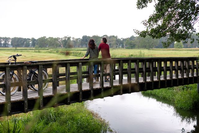 Stel pauzeert tijdens fietstocht op een bruggetje waar ze genieten van het uitzicht bij de Drentsche Aa.