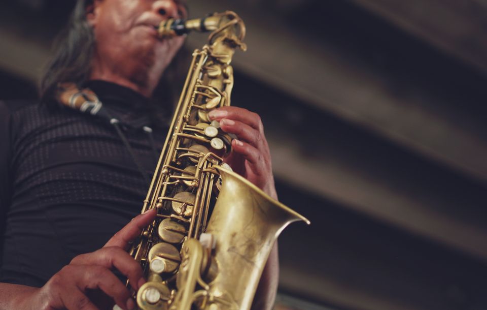 Close-up van een persoon die op de saxofoon speelt.