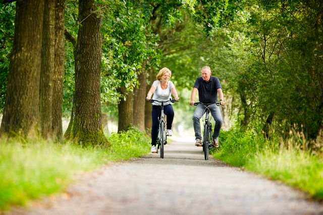 Een man en vrouw fietsen door een bos in Drenthe.