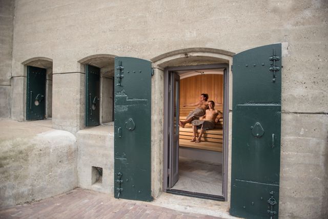 Zicht op mensen met handoek om door een fort raam in een sauna
