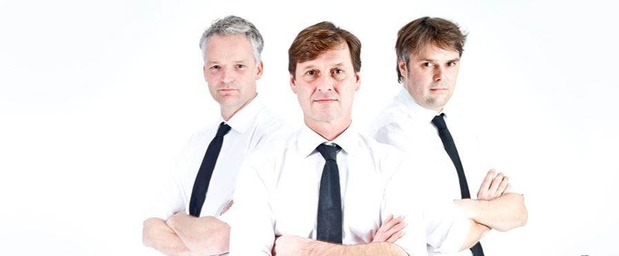 Drie mannen in een wit overhemd en bretels