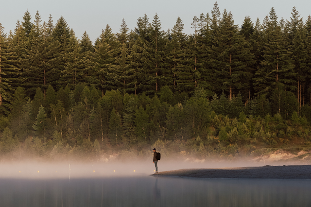 Een man staat in de ochtendmist aan de rand van het water bij het Gasselterveld