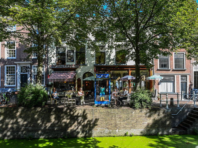 Mensen die lunchen langs de gracht in Delft aan de Oude Delft bij café uit de kunst