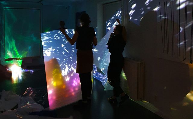 Twee bezoekers genieten van lichtkunst in donkere galerie