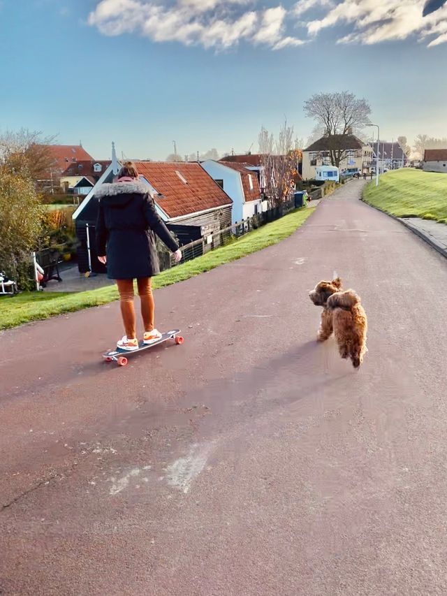 Lydia is in de ochtend met hond Sjef aan het longboarden in Workum