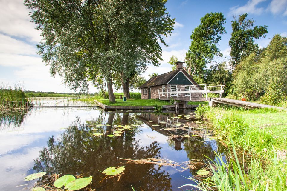 Vervenershuisje in Nationaal Park Weerribben-Wieden. Water en rietlandschap met wit bruggetje.