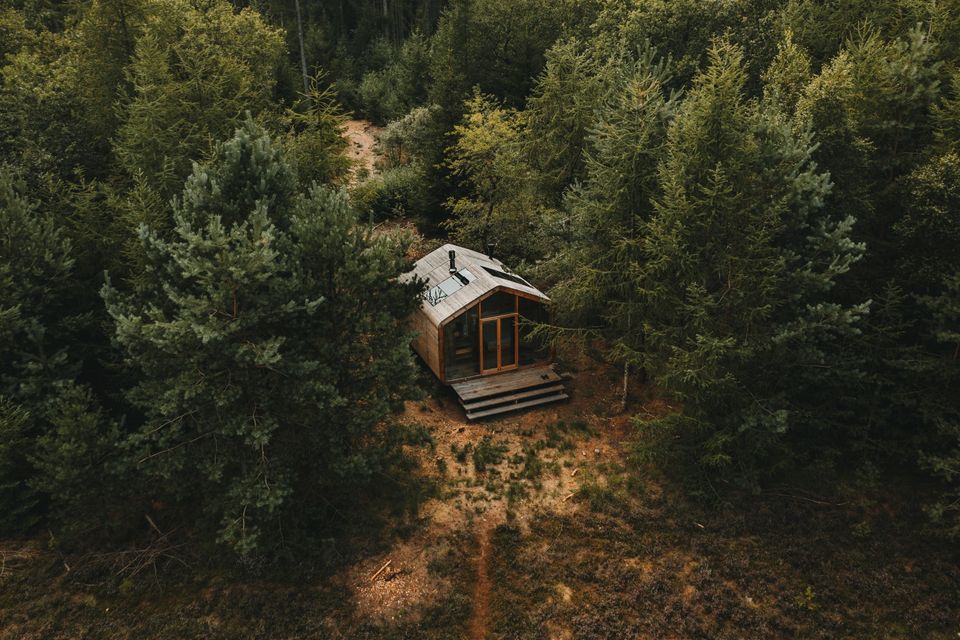 Een cabin midden in het bos vanuit de lucht gezien.