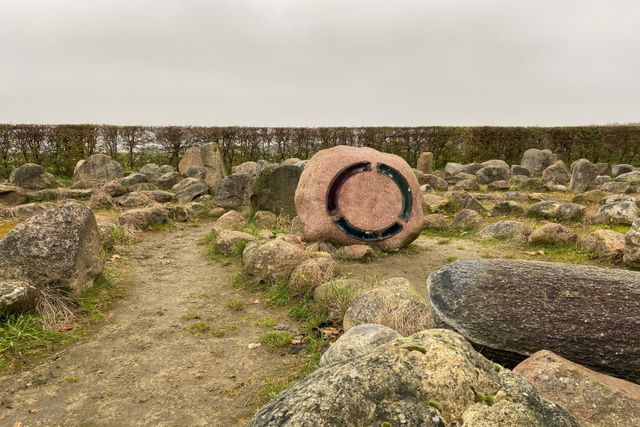 Een grote steen met daarop een cirkel wordt omringd door kleine keien en markeert de vindplaats van het meisje van Yde.