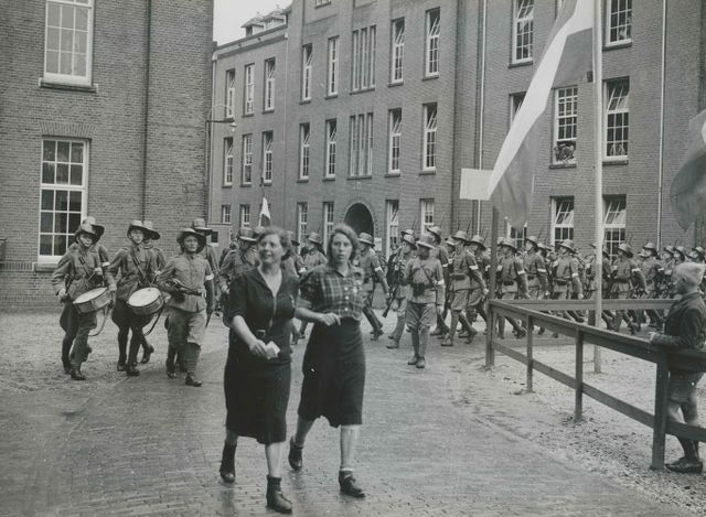 Het detachement van de Koloniale Reserve onder commando van de kapitein M.Th. Slagter (midden op de foto) keert terug van het parcours van 40 km in de Prins Hendrik Kazerne op de eerste dag van de 29e Vierdaagse. Voorop gaan twee dames; links mevrouw M. Klaver-Budding.