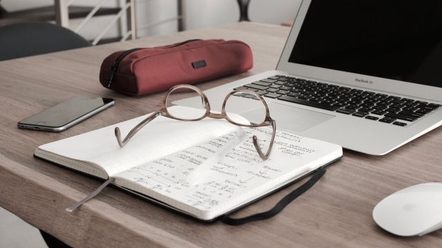 Desk with notebook, glasses and laptop