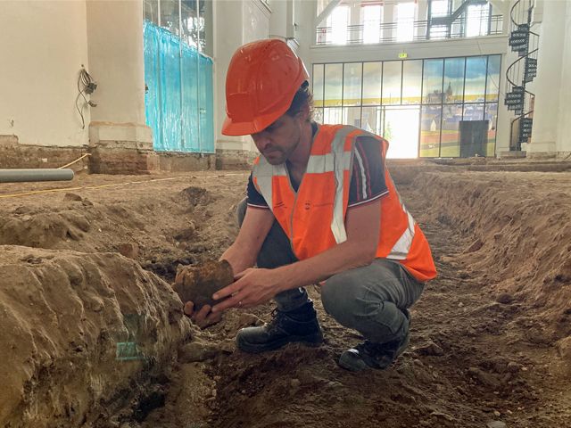 Een archeoloog houdt een opgegraven schedel in zijn hand.