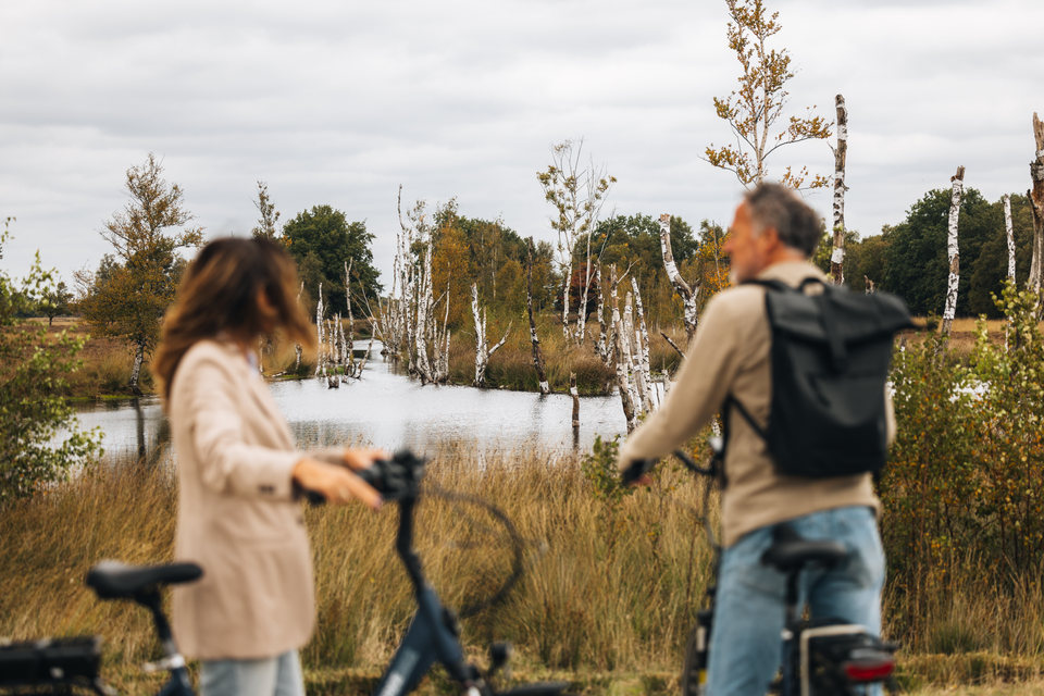 Een man en een vrouw zijn in het Bargerveen even van de fiets afgestapt om van het veenlandschap te genieten