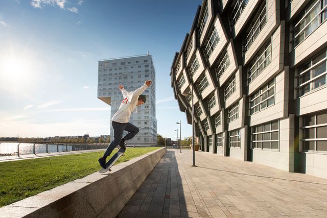 Een urban skateboarder doet een truc naast The Wave en the Silverline, architectuur aan het water in Almere, Flevoland