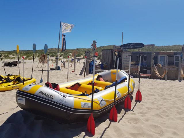 De foto van Bureau Vlieland toont een gele rubberboot met 8 roeispanen op het strand van Vlieland