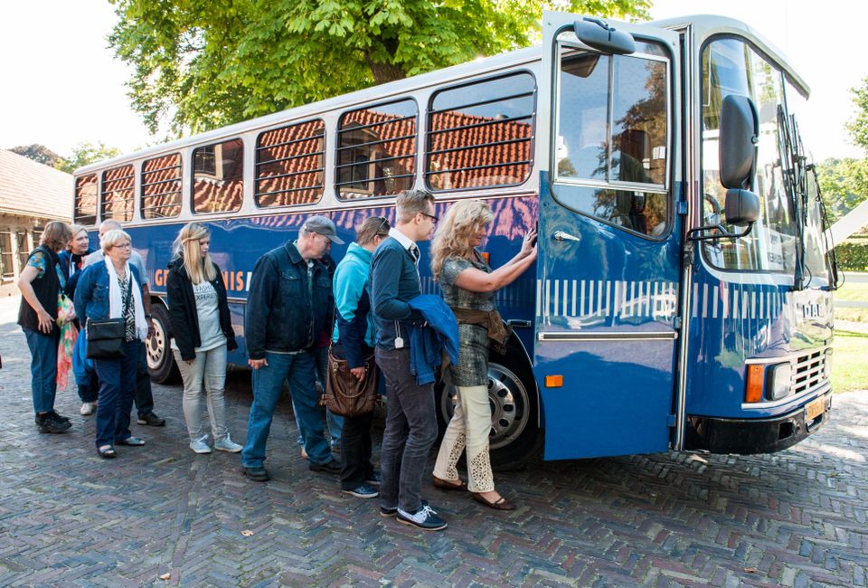 Groep mensen die in een oude boevenbus stappen voor een rondrit door Veenhuizen.