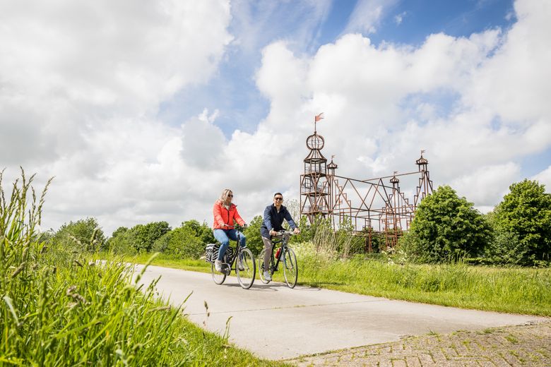 Man en vrouw fietsen voor de Stania State in Friesland