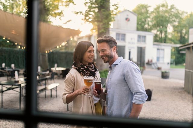 Man en vrouw proosten lachend met een Maallust biertje.