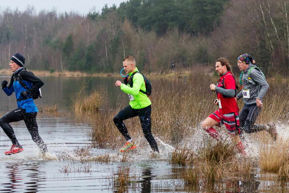 Trailrunners rennen in de winter door het water.