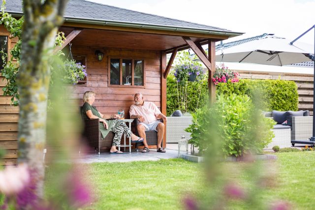 Een echtpaar zit voor hun tuinhuis op het terras van hun woning in Lelystad, Flevoland
